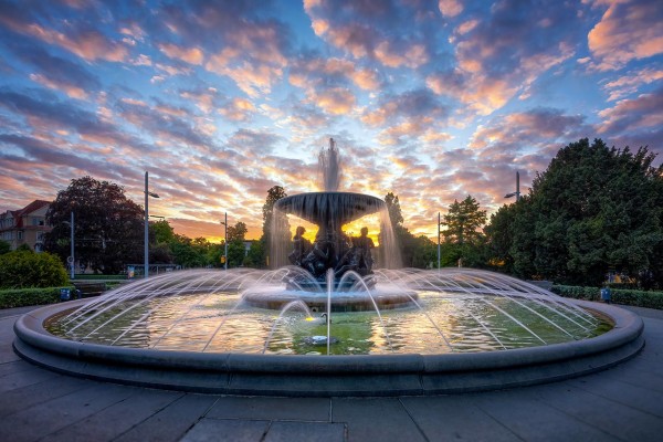 Wandbild Dresden - Springbrunnen „Stille Wasser“ am Alberplatz zum Sonnenuntergang (Motiv 01098)